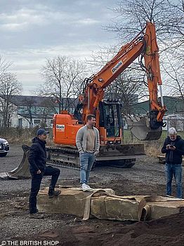 Robert Siebel (Mitte) mit zwei Mitarbeitern der Gartenbaufirma Peter Berg Gartendesign, die vor einem Bagger und auf großen Findlings-Steinen stehen