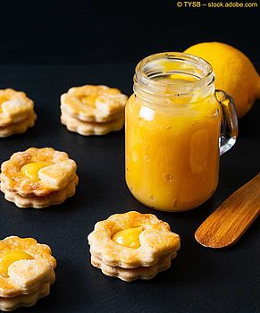 Mehrere Jammie Dodgers mit Lemon Curd, ein Glas Lemon Curd und eine Zitrone