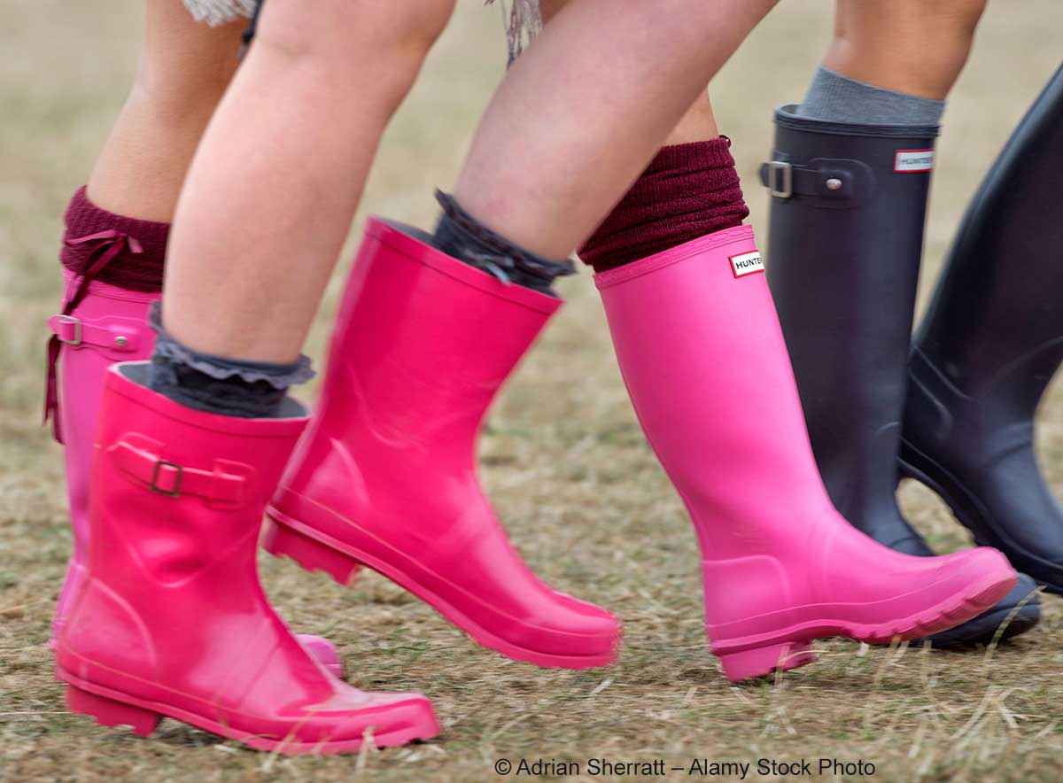 Beine von drei Personen, die Gummistiefel in Pink und Schwarz tragen