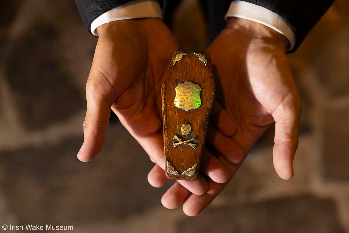 Miniatur-Sarg wird in zwei Händen gehalten