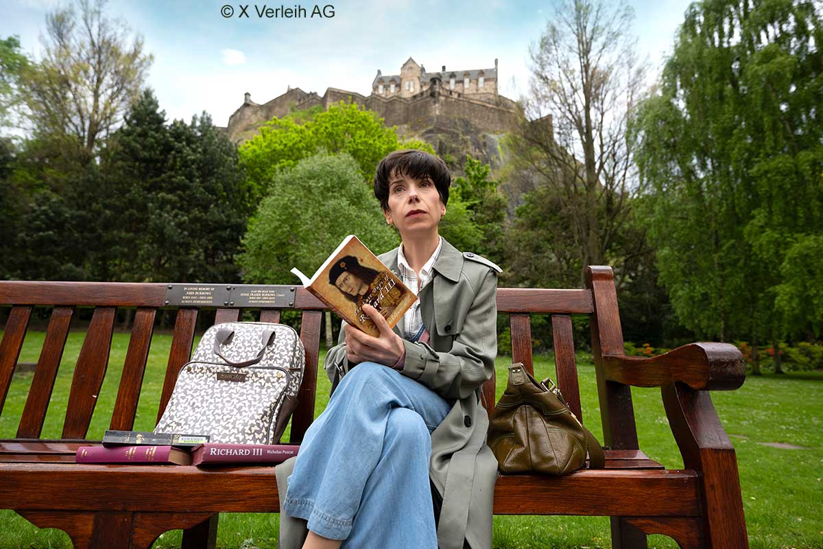 Sally Hawkins als Philippa Langley sitzt auf einer Bank unterhalb von Edingburgh Castle und liest Bücher über König Richard III. Sally Hawkins als Philippa Langley sitzt auf einer Bank unterhalb von Edingburgh Castle und liest Bücher über König Richard III.