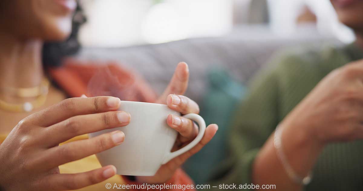 Zwei Frauen sitzen gemeinsam auf der Couch, trinken Kaffee und unterhalten sich. Zwei Frauen sitzen gemeinsam auf der Couch, trinken Kaffee und unterhalten sich.