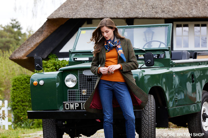 Winterliche Brit-Chic-Mode Die besten Outfits für Spaziergänge im frostigen Dezember Eine Frau mit Jacke, Pullover und Schal vor einem grünen Landrover